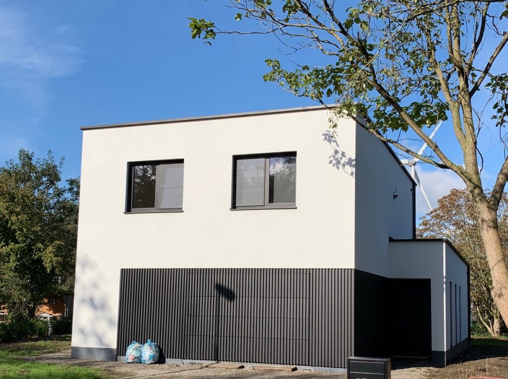 Nieuwbouw met gevelisolatie en gevelbepleistering: witte crepi en arduinplint